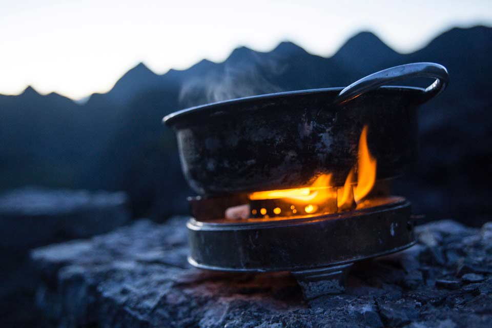 kettle on an open flame stove on a rock